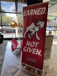 a red sign that says earn and not given in front of a building with large windows