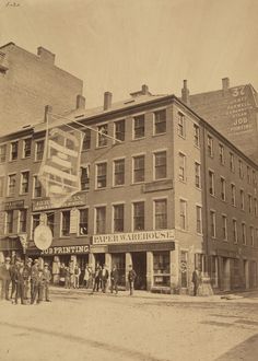 an old black and white photo of people standing in front of buildings