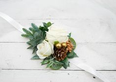 a bridal bouquet with white roses, pine cones and greenery on a wooden surface