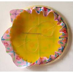 a yellow and pink paper plate sitting on top of a white table next to a wall