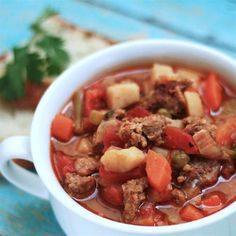 a close up of a bowl of food with meat and vegetables in it on a table