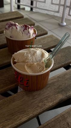 two ice creams sitting on top of wooden benches