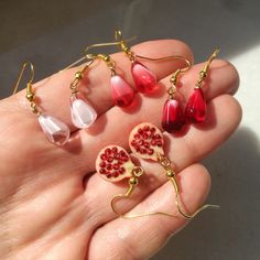 Set of unique, elegant pomegranate seed earrings. Fruit seed in ruby red, pink rose and crystal white colors or half fruit charm with tiny seeds inside. Finished with gold. Minimalist, memorable dangle earrings #pomegranateearrings #pomegranateseed #seedearrings #pomegranatejewelry #pomegranatelover #minimalistearrings #redseed #redpomegranate #whitegoldearrings #cutetinyearrings Pomegranate Seed Jewelry, Snow White Earrings, Pomegranate Accessories, Persephone Design, Ruby Aesthetic, Fruit Accessories, Interesting Earrings, Cottagecore Earrings, Pomegranate Jewelry