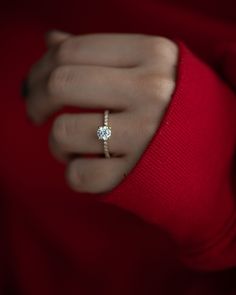 a woman's hand with a diamond ring on her left wrist, wearing a red sweater