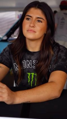 a woman sitting at a table with a laptop in front of her and looking off to the side