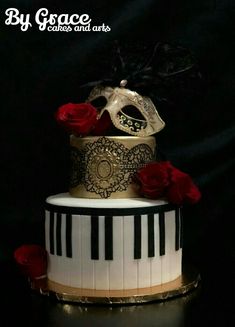 a three tiered cake decorated with black and white piano keys, red roses and a mask