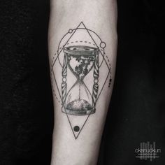 a man's arm with an hourglass tattoo on it