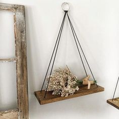 two hanging shelves with flowers on them and one holding a vase filled with dried flowers