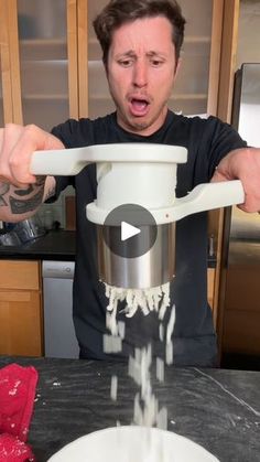 a man is pouring water into a pot on the kitchen counter with his hands in front of him