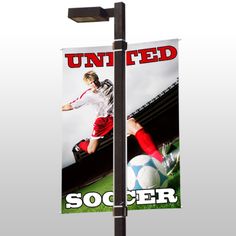 a soccer banner hanging from a pole on the side of a field with a man kicking a soccer ball