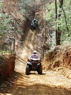 a man riding an atv down a dirt road