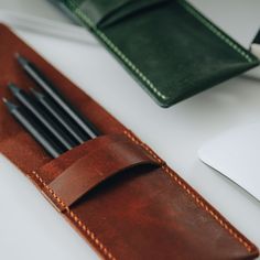 a leather pen case with four pens in it