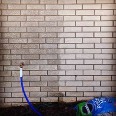 a brick wall with a blue hose attached to it next to a bag of garbage