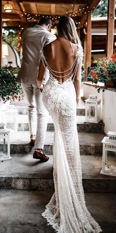 a bride and groom walking down the steps together in their wedding dress with open back