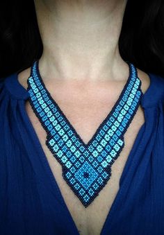 a woman wearing a blue shirt with a beaded necklace on it's neck