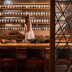 a woman standing in front of a counter filled with jars