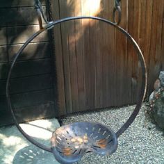 a metal swing hanging from a wooden fence