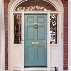 a blue front door on a brick building with an arched window and white trim around it