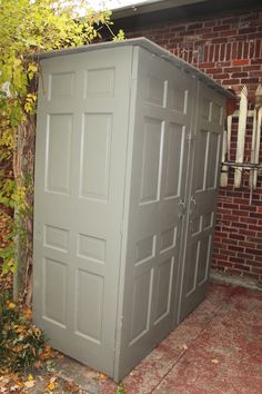 a gray storage shed sitting next to a brick building