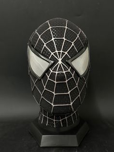 a spiderman mask with glowing eyes on a black background, close up view from the front