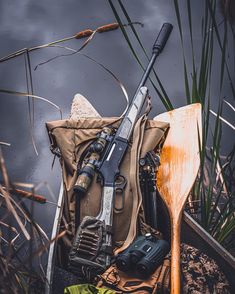 an assortment of fishing equipment sitting on the ground next to some water and reeds