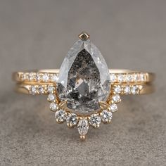 an engagement ring with a pear shaped gray diamond surrounded by smaller white and yellow diamonds