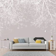 a living room with a couch, rug and wallpaper that has white branches on it