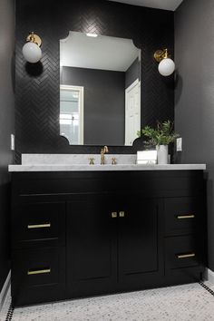 a bathroom with black and white walls, gold fixtures and a large mirror over the sink