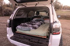 the back end of a white truck filled with blankets and pillows