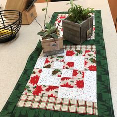 a table topped with potted plants on top of a green mat covered in red and white fabric