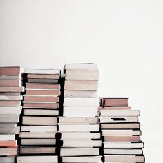 a stack of books sitting on top of each other in front of a white wall