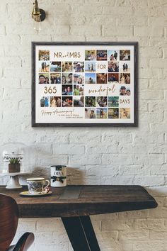 a wooden table topped with two coffee cups and a framed photo on the wall above it