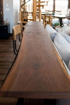 a long wooden table sitting in the middle of a living room next to couches