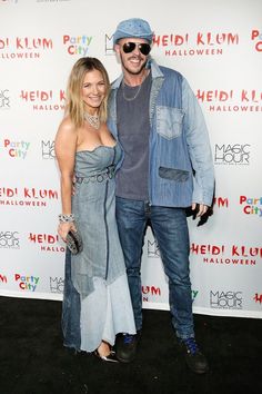 a man and woman pose for the camera on the red carpet in front of a backdrop