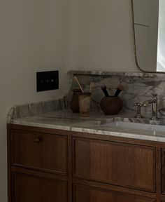 a bathroom vanity with marble counter top and wooden cabinetry, along with a large mirror above it