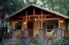 a small house made out of rocks and stone veneers with wood trimming around the front porch