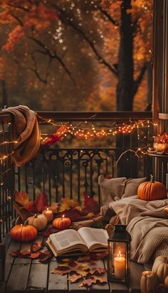 an open book sitting on top of a wooden table next to pumpkins and candles