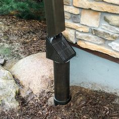 a grill sitting on top of a stone wall next to a rock and grass area