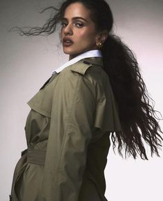 a woman with long hair wearing a trench coat