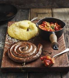 a wooden cutting board topped with food and a bowl filled with sauce next to it