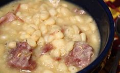 a bowl filled with beans and ham on top of a table