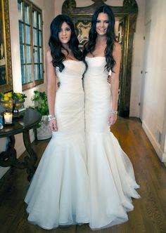 two beautiful women in white dresses standing next to each other