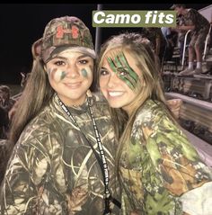 two girls with face paint on their faces at a sporting event in the night time