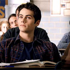 a group of people sitting at desks in a classroom with one man looking up