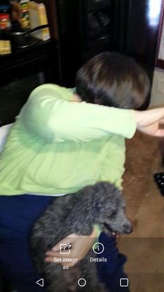 a woman sitting on the floor petting a dog with her arm around another person's head