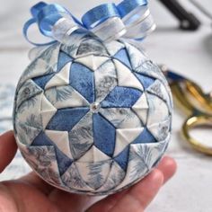 a hand holding a blue and white ornament