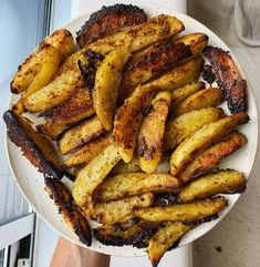 a white plate topped with french fries on top of a table next to a window