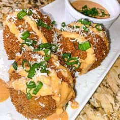 three fried food items on a plate with sauce and parmesan toppings next to a bowl of dipping sauce