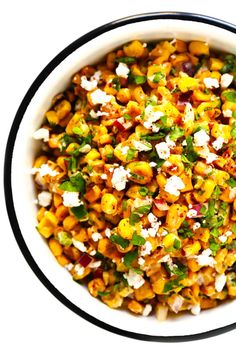 a white bowl filled with corn and feta cheese