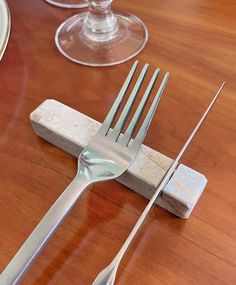 a fork and knife sitting on top of a wooden table next to two wine glasses